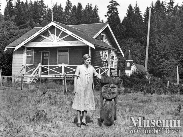 Mrs. Knox with a carving at the Cape Mudge Village, Quadra Island