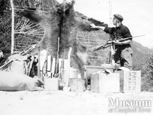 Hunter with grizzly bear hide and hunting equipment